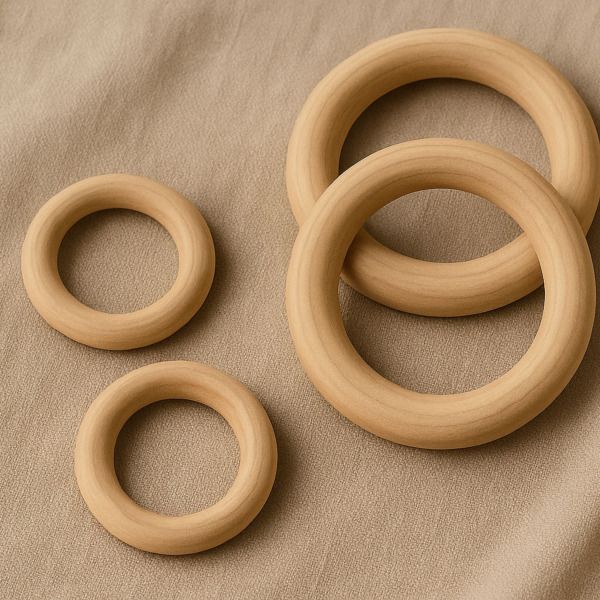 vier houten ringen van verschillende formaten op beige ondergrond, gladgeschuurd en natuurlijk voor diverse diy-projecten